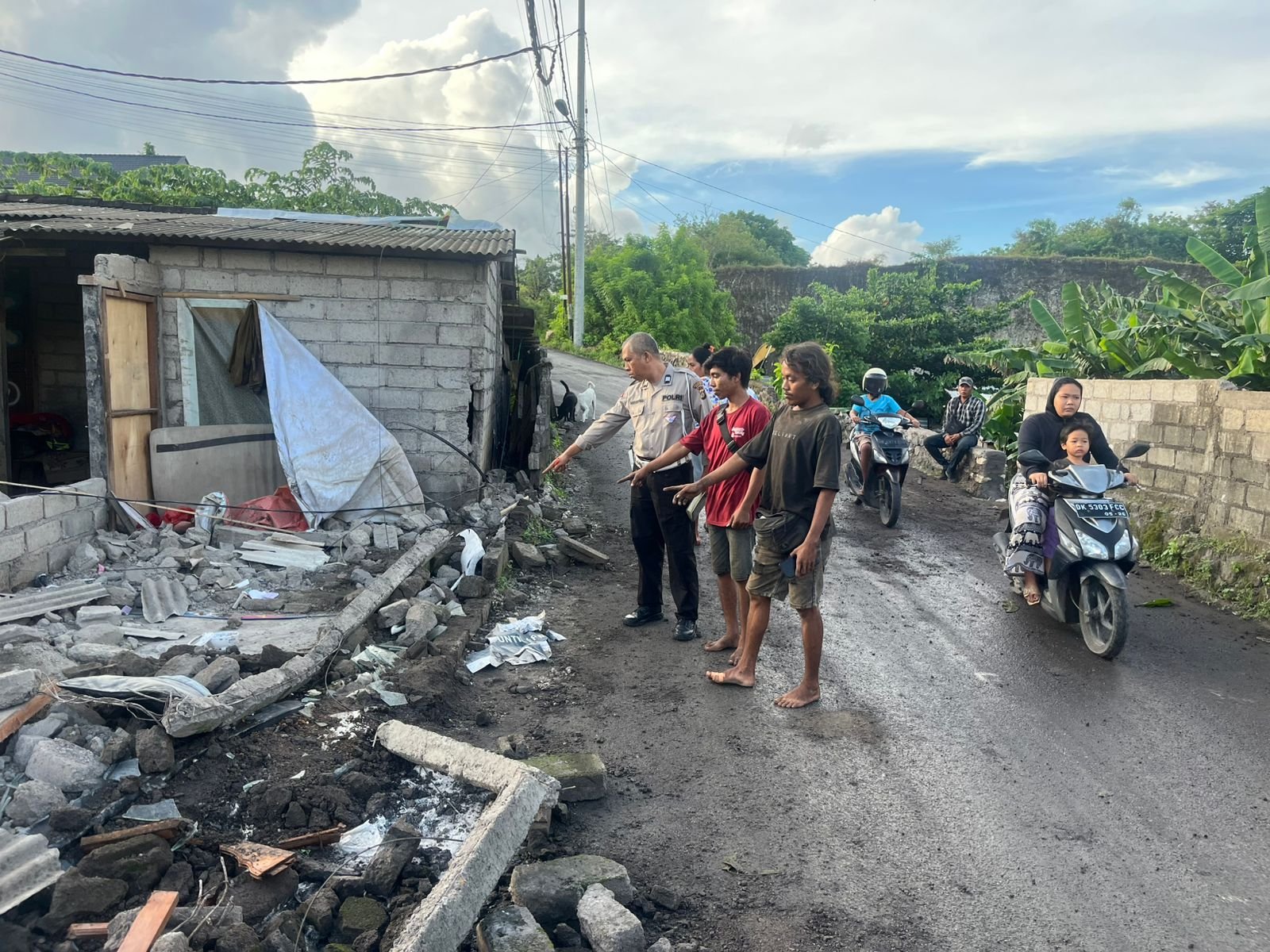 KECELAKAAN TRUK-Polisi menunjuk lokasi kecelakaan truk Fuso tabrak rumah warga di Jalan Pura Pengulapan, depan Kampung Gar, Banjar Giri, Ungasan, Kuta Selatan, Badung.